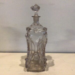 Klukflaske korpus pålagt rigler på hørnerne og rosetter på skuldre og bundparti. Halsen indboret for massiv prop med rosetter